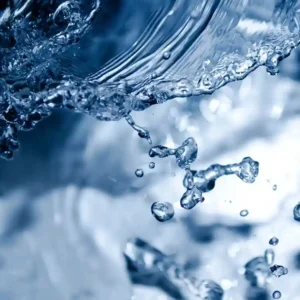 Close-up of water splashes and droplets in shades of blue, capturing the dynamic movement and fluidity of liquid.