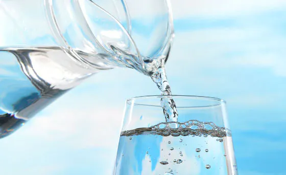 A glass of pure treated water poured from a pitcher, showcasing the clarity of professional water treatment in Cape Coral.